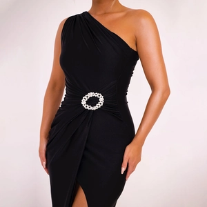 Detail of elegant black one-shoulder dress with side slit and sparkling rhinestone brooch
