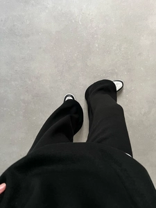 Detail view of black high-waist wide-leg trousers with elegant drape on concrete floor