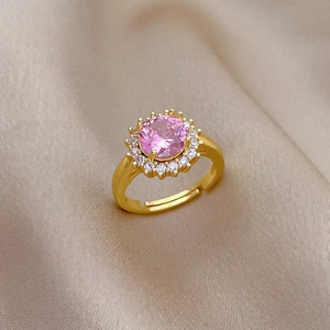Vue macro d'une bague avec pierre rose et diamants blancs sur soie champagne