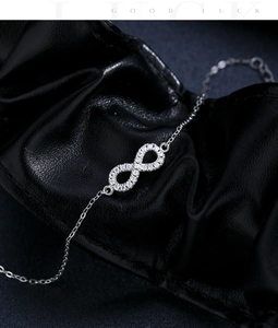 Detail of silver infinity bracelet with sparkling stones on black leather background