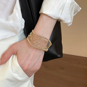 Detailed shot of a wide gold mesh cuff bracelet with wire weaving and bead accents
