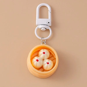 Close-up of a realistic steamed bun keychain with a yellow bamboo steamer and metal hook