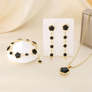 Golden jewelry set with black clover charms featuring long tassel earrings and necklace