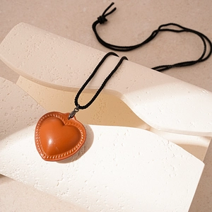 Vintage orange faux leather heart pendant necklace with stitched edges on white stone