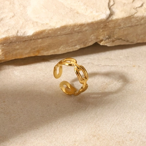 Dettaglio di anello a catena regolabile placcato oro su pietra naturale e sabbia