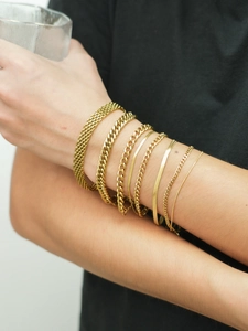 Detail view of stacked 18K gold-plated stainless steel Cuban and snake chain bracelets