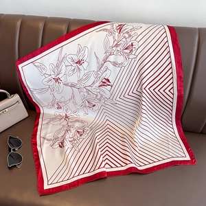 Elegant red and white floral silk scarf displayed on a sofa with fashion accessories