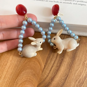 Détail de boucles d'oreilles lapin et perles au design vintage avec clous rouges