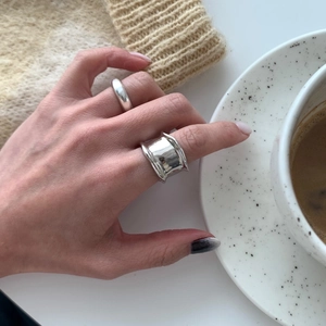 Close-up of a minimalist irregular wave ring and smooth band set in polished silver
