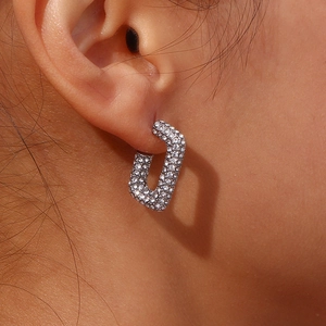 Dettaglio di un orecchino a cerchio rettangolare argento con zirconi su una modella