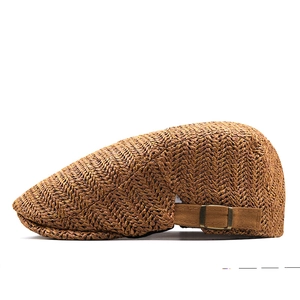 Detail of tan woven straw flat cap featuring breathable V-weave and adjustable side buckle