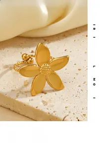 Detailed close-up of golden floral ring with textured petals on natural stone