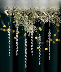 Close-up of transparent acrylic icicle ornaments on pine branches with warm bokeh lights