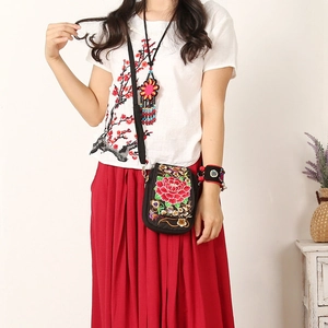 Detail view of ethnic embroidery crossbody bag with red peony floral pattern on black fabric