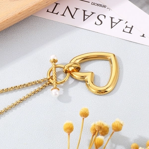 Détail du collier coeur doré avec fermoir en T et accents de perles élégantes