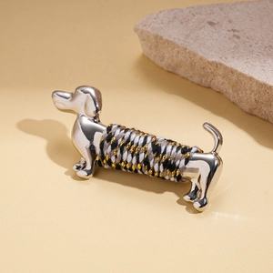 Macro detail of silver dachshund brooch featuring tricolor braided rope on metal