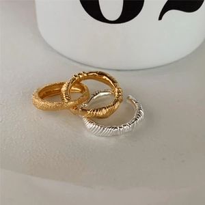 Detail of three-piece silver knot ear cuff set with matte gold and twisted textures