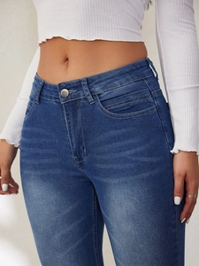 Close-up of high-waisted blue jeans with metal button fly and classic pockets detail