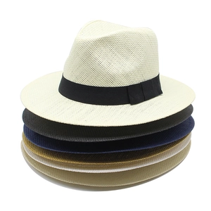 Close-up of stacked panama straw hats in beige black and khaki with ribbon detail