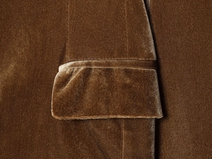 Gros plan sur la couture de la poche d'un blazer en velours marron au fini brillant