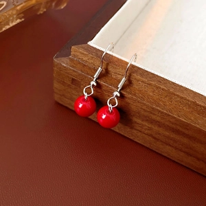 Gros plan détaillé de boucles d'oreilles en perles rouges avec crochets en argent