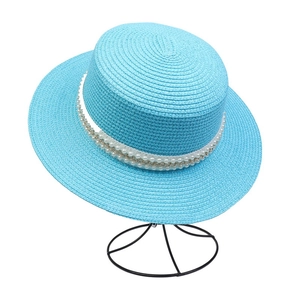 Detail of sky blue straw hat with wide brim featuring pearl and gold chain trim