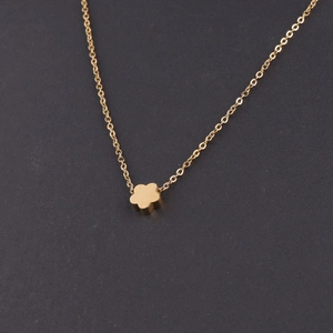 Close-up of minimalist golden flower pendant on a fine link chain necklace with polished finish