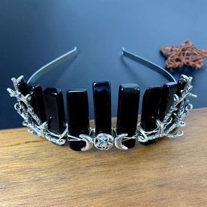 Macro detail of gothic crystal crown with silver moon and twig accents on wooden base