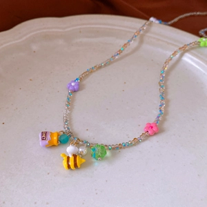 Detailed close-up of colorful honey bee and flower charms on a beaded necklace
