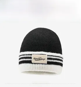 Détail du bonnet en tricot rayé noir et blanc avec un écusson en cuir logo PineCrest
