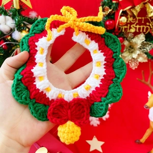 Close-up of hand-knitted Christmas pet scarf with red, green and white festive patterns