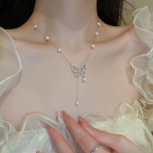 Close-up of gold plated butterfly necklace with freshwater pearls and tassel on model