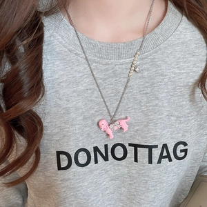 Close-up of pink puppy pendant necklace with zircon bow and pearl accent on a model