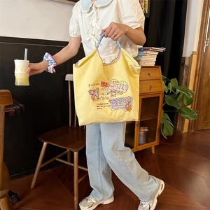 Detail der gelben Canvas-Tasche mit bunter Schaf-Stickerei in einer gemütlichen Café-Szene