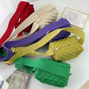 Flat lay of colorful popcorn textured crossbody bags in red, beige, purple and green