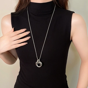 Collier minimaliste avec pendentif torsadé porté sur un pull noir chic et moderne