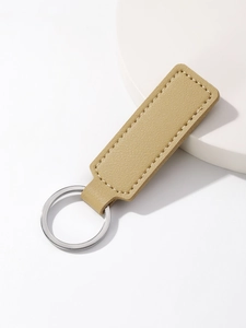 Detail of light brown lychee grain leather keychain with fine stitching on white tray