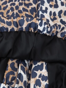 Close-up of leopard print fabric texture and black rib-knit stitching on baseball jacket