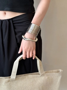 Close-up of stacked silver bangles with irregular wavy design on female wrist