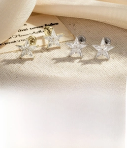 Macro detail of star-shaped zircon stud earrings with screw back closure in gold