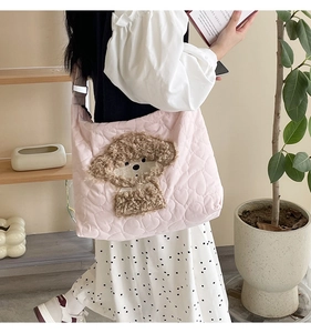 Close-up of pink quilted tote bag featuring a cute plush puppy and heart stitching