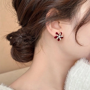 Macro shot of a model wearing a burgundy flocked snowflake earring with a pearl center