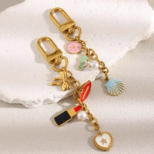 Détail de porte-clés dorés 18K avec breloques en émail, perles et strass brillants