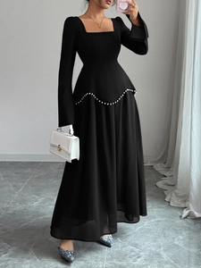 Détail d'une robe noire élégante à manches longues avec bordure perlée et encolure carrée