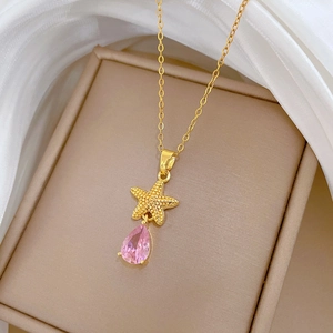 Starfish pendant necklace with pink teardrop crystal on a beige jewelry box