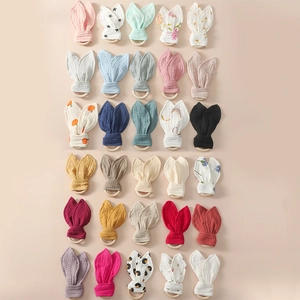 Flat lay of cotton rabbit ears teething rings in various colorful patterns and fabrics
