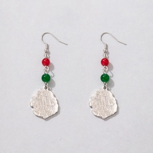 Detail of festive Christmas earrings with red and green pearls on irregular silver pendants