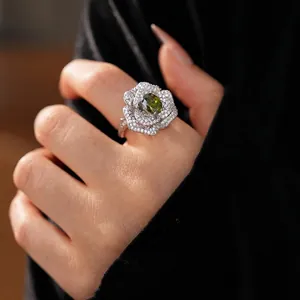 Luxury silver flower ring with zircon petals and an oval emerald center stone on hand