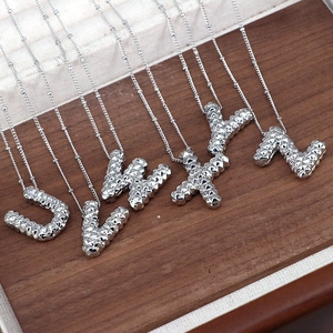 Detailed macro view of silver alphabet pendants U to Z with textured 3D relief on a tray