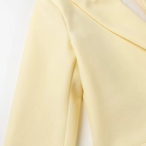 Detail of cream yellow long coat showing the fine fabric texture and notched lapel